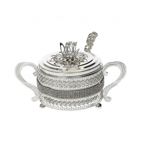 Glass sugar bowl with a diamond-shaped metal holder and a spoon